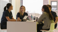 Group of four students talking around a table.